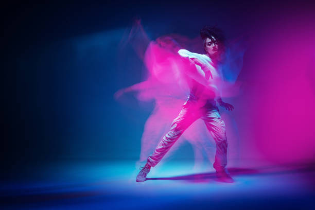 Dancing mixed race girl in colourful neon studio light. Female dancer performer show expressive hip hop dance. Long exposure. High quality photo